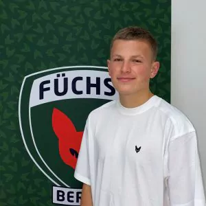 Auf dem Bild sieht man Julius Schröder vor dem Füchse Logo stehen. Julius absolviert ein duales Studium bei den Füchsen. Er ist vorallem im Bereich Tennis zuständig.